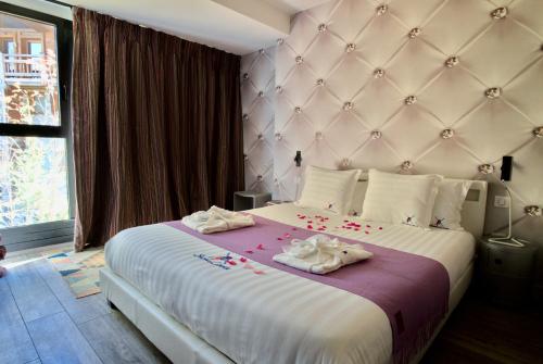 a bedroom with a large bed with towels on it at Snow Lodge Hotel Courchevel 1850 in Courchevel