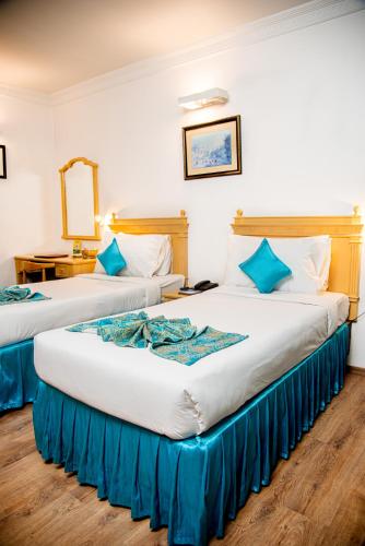 two beds in a hotel room with blue pillows at Golden Parkk Hotel in Kolkata