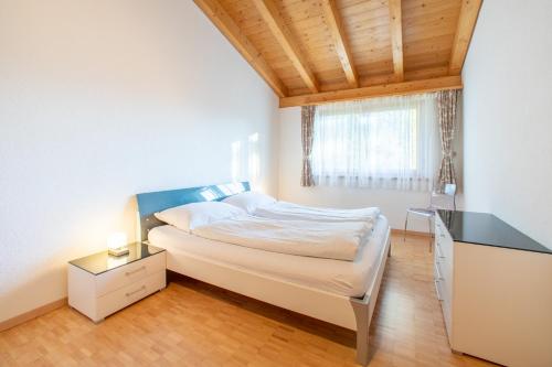 a bedroom with a bed with a desk and a window at Casa Miraval in Flims