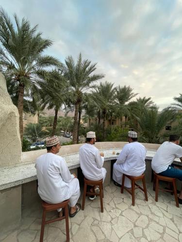 a group of men sitting around a counter looking at palm trees at نزل البستان Bustan lnn in Nizwa