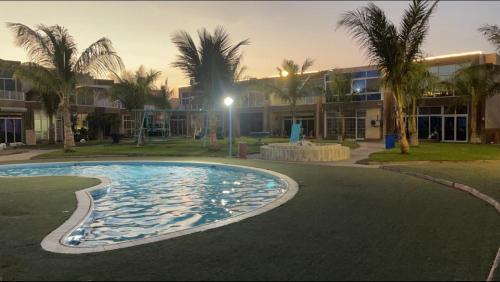 a swimming pool in front of a building with palm trees at شاليه جزيره السعاده in Obhor