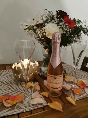 - une bouteille de vin, 2 verres et des fleurs sur une table dans l'établissement La bulle suspendue, à Bassevelle