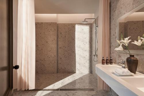 a bathroom with a shower and a white sink at Le Récit Boutique Hôtel de Dalat in Da Lat