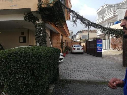 a man standing in front of a building with a car at Happy Stay Guest House in Abbottābād