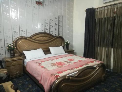a bedroom with a large bed with a red blanket at Happy Stay Guest House in Abbottābād