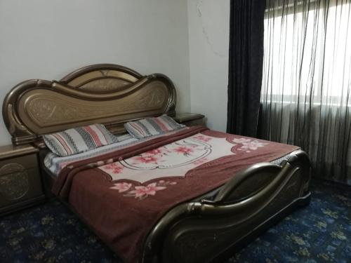a bedroom with a bed with a red comforter at Happy Stay Guest House in Abbottābād