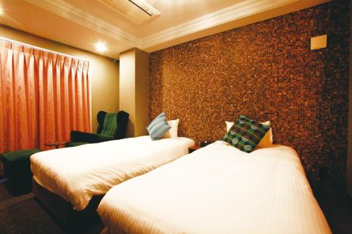 a hotel room with two beds and a brick wall at HOTEL STATE TENNOJI in Osaka