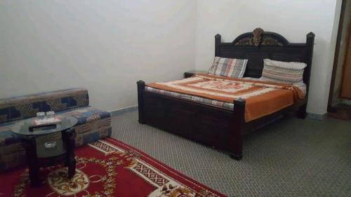a bedroom with a bed and a couch at Happy Stay Guest House in Abbottābād