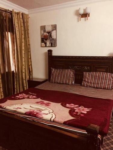 a bedroom with a large bed with a red comforter at Happy Stay Guest House in Abbottābād