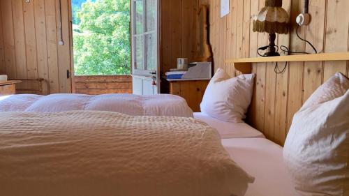 a bedroom with two beds with white sheets and a window at Berghaus Iffigenalp in Lenk