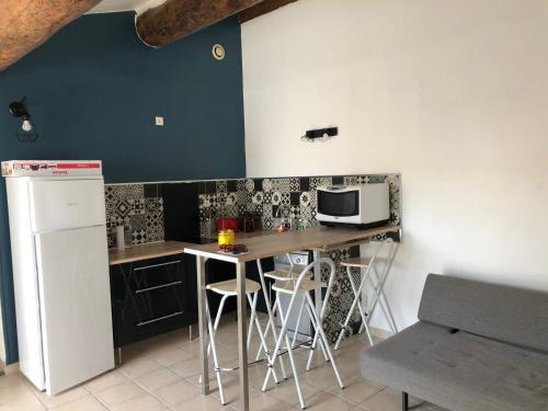 - une cuisine avec une table, des tabourets et un four micro-ondes dans l'établissement Appartement loft toit/terrasse, à Sigean