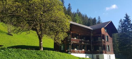 a large house on a hill with a tree at Berghaus Iffigenalp in Lenk