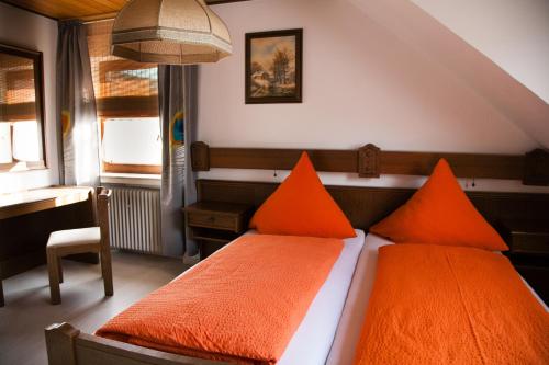 a bedroom with two orange pillows on a bed at Herzog's Ulsterbrücke in Tann