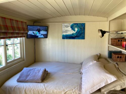 a small bed in a room with a tv on the wall at The Rowan Shepherds Hut in Eyemouth