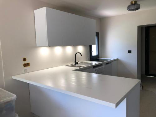 eine Küche mit einer weißen Theke und einem Waschbecken in der Unterkunft Maison pieds dans l eau avec piscine et clim in Linguizzetta