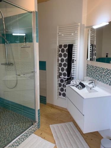 La salle de bains est pourvue d'une douche en verre et d'un lavabo. dans l'établissement Gîte Manulau, à Turqueville
