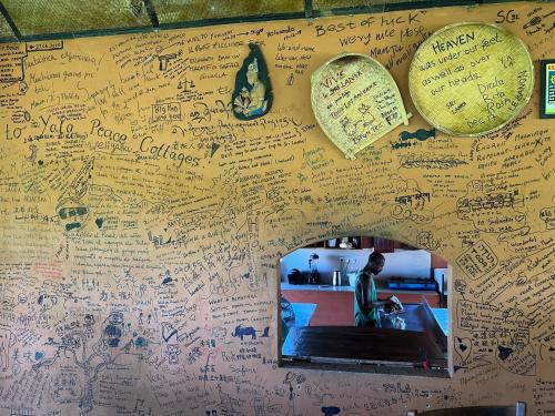 a wall covered in writing on a wall with a mirror at Yala Peace Cottages in Tissamaharama