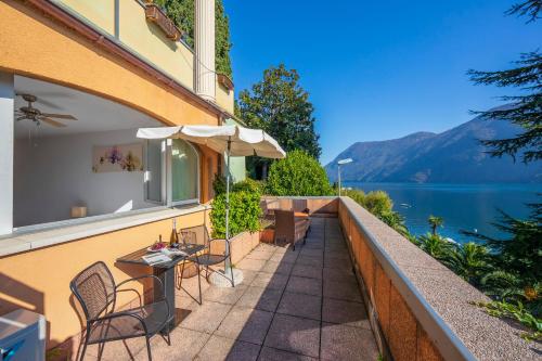a balcony with tables and chairs and a view of a lake at Apartments Gelsomino, Orchidea and Magnolia - Happy Rentals in Castagnola