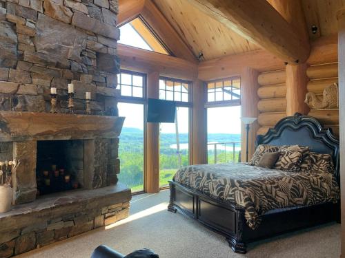 a bedroom with a stone fireplace in a log cabin at Mont du Lac Resort in Carlton