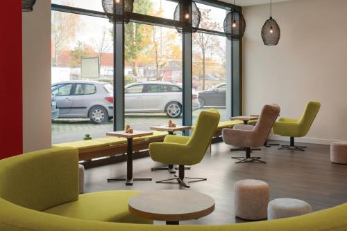 a waiting room with chairs and tables and windows at Super 8 by Wyndham Augsburg in Augsburg