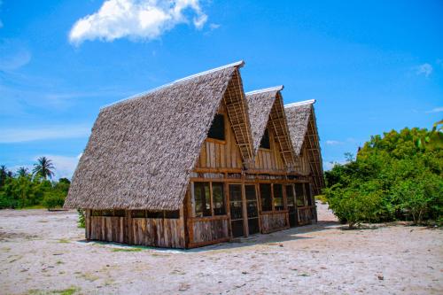 a large wooden building with a large roof at Mikoko Beach & Cottages in Bagamoyo