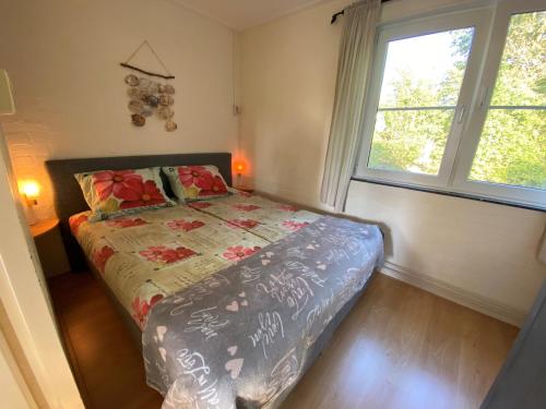 een slaapkamer met een bed en 2 ramen bij Robbenoort 45 in Lauwersoog