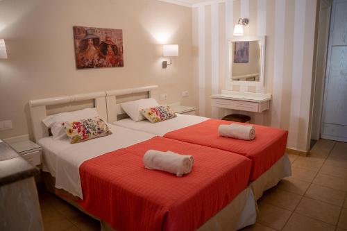 a bedroom with two beds with red and white sheets at Blue Sky Apartments in Malia