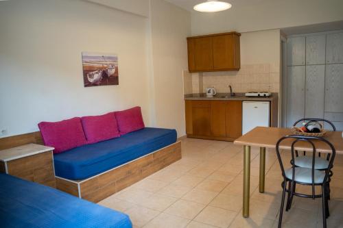 a living room with a blue couch and a kitchen at Blue Sky Apartments in Malia