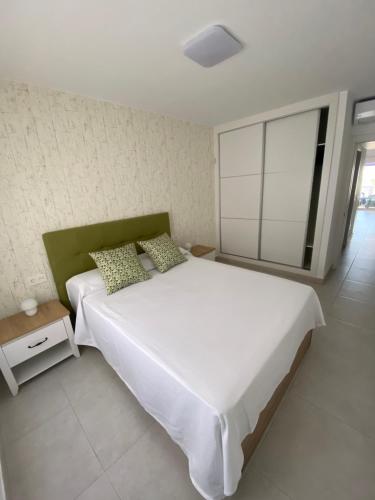 - une chambre avec un grand lit blanc et une fenêtre dans l'établissement Piso tranquilo,piscina comunitaria.Zona turística, à Costa Teguise