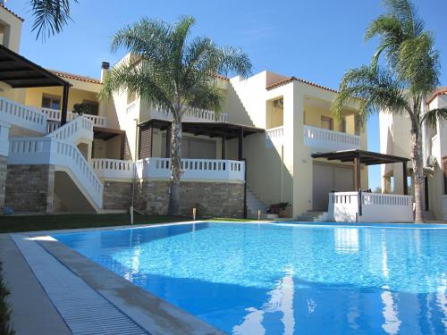 a swimming pool in front of a house with palm trees at Villa Pandora - Angela & Michali in Maleme