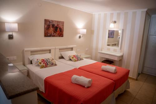 a bedroom with two beds and a red blanket at Blue Sky Apartments in Malia