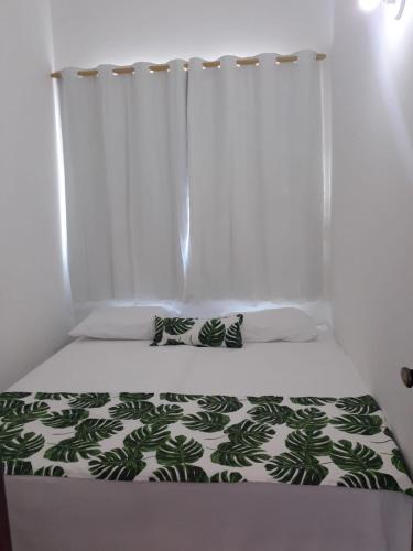 a bed with a green and white comforter and a window at Casas Bérgamo in Morro de São Paulo