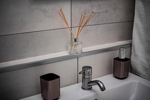 a bathroom sink with a vase with sticks in it at Amica Vendégház in Zalakaros