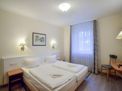 ein Schlafzimmer mit einem großen weißen Bett und einem Tisch in der Unterkunft Dünenpark Binz - Komfort Ferienwohnung mit 1 Schlafzimmer und Terrasse im Erdgeschoss 115 in Binz