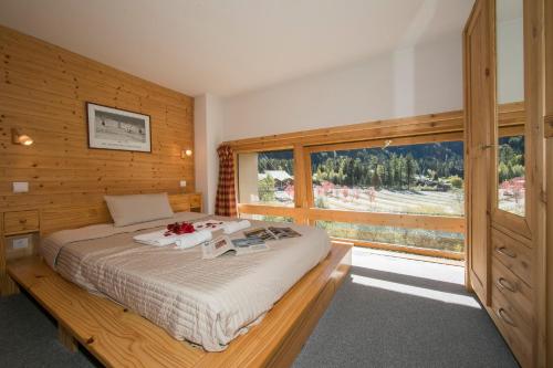 ein Schlafzimmer mit einem Bett und einem großen Fenster in der Unterkunft Résidence Grand Roc - Ancolies 213 - Happy Rentals in Chamonix-Mont-Blanc