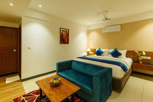 a hotel room with a bed and a blue couch at Royal Ace Boutique Hotel in Bengaluru