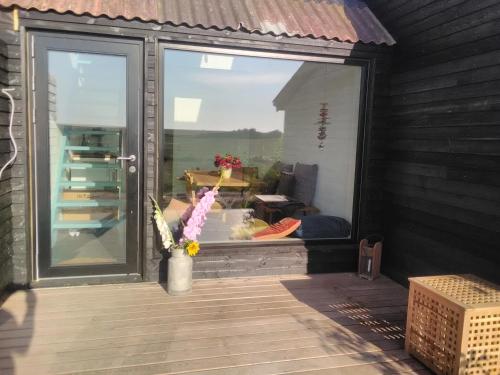 a patio with a window and a vase of flowers at Rikke og Franks Svineri in Lemvig