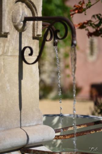 a water chain hanging from the side of a fountain at Le Mas Carré Séguret in Séguret