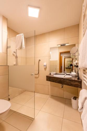 a bathroom with a glass shower and a sink at Burgdorfs Hotel & Restaurant in Hude