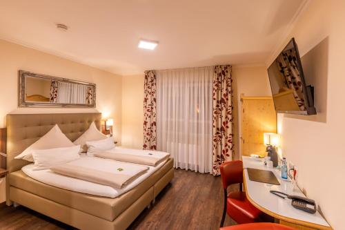 ein Hotelzimmer mit einem Bett und einem Schreibtisch in der Unterkunft Burgdorfs Hotel & Restaurant in Hude