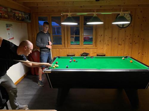 a man playing pool in a room with a pool table at Domaine du Bugnon in Lac des Rouges Truites