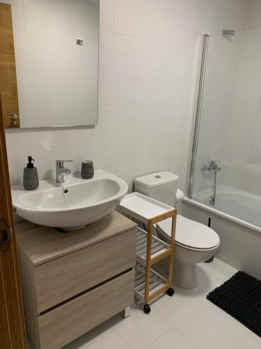 uma casa de banho branca com um lavatório e um WC em Apartamento Porta da Vila em Viveiro