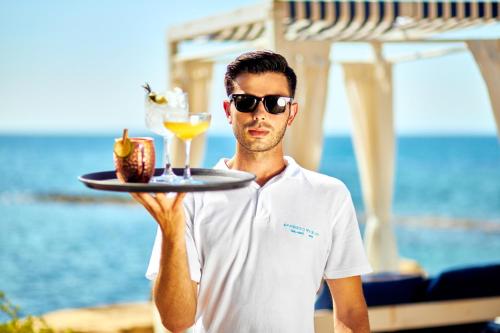 a man in sunglasses holding a tray with a drink at Approdo Resort Thalasso Spa in Castellabate