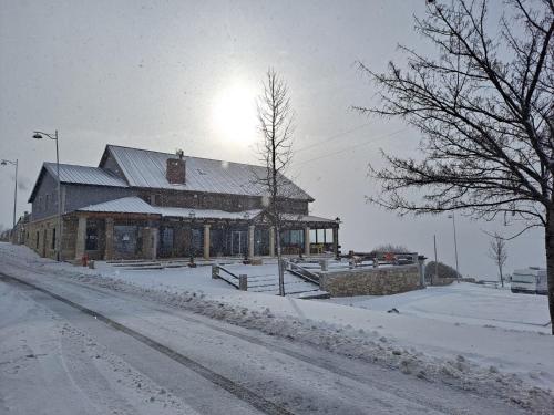 a building on a street with snow on the ground at Alojamento de montanha in Penhas da Saúde
