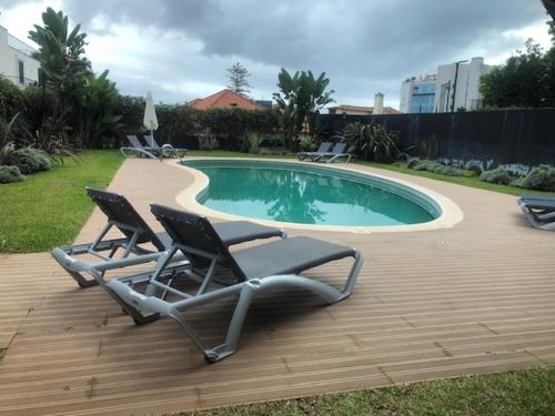two lounge chairs sitting next to a swimming pool at Astro Madeira Apartments in Funchal