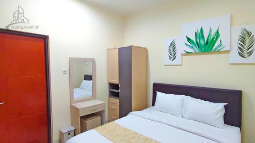 1 dormitorio con cama y espejo en Atmosfer Guest House Sentul, en Bogor