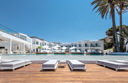 a swimming pool with chaise lounge chairs next to a resort at Kantouni Beach Boutique Hotel in Panormos Kalymnos