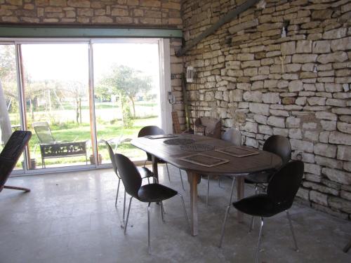 einen Tisch und Stühle in einem Zimmer mit Ziegelwand in der Unterkunft Les moinillons - Piscine à 28 degrés en service toute l'année in Ancy-le-Franc