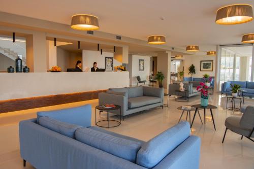 a lobby with blue couches and chairs and a bar at Resort La Battigia Beach & Spa in Alcamo Marina