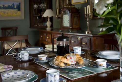 a table with a plate of croissants and a coffee pot at The Old Manor House in Halford